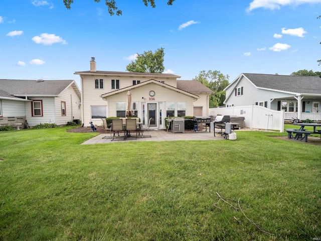 rear view of house with a lawn and a patio