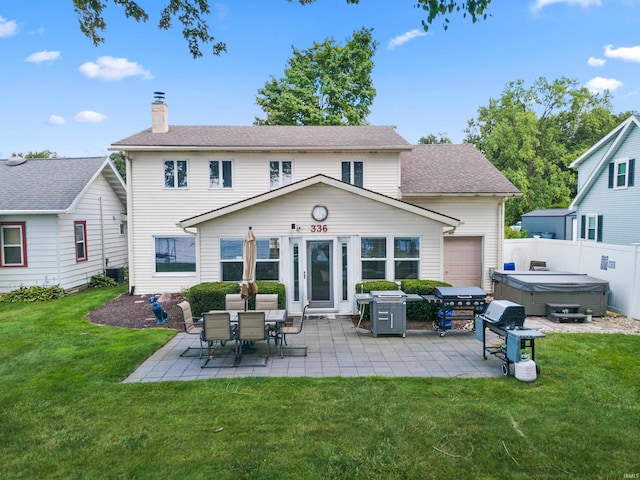 rear view of house featuring a hot tub, a yard, and a patio