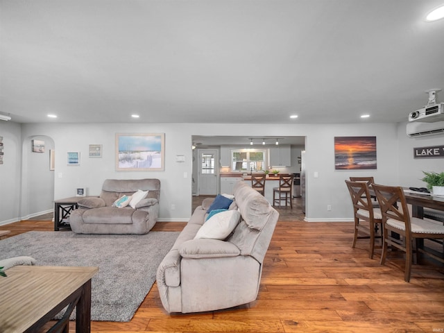 living room with a wall unit AC and light hardwood / wood-style flooring