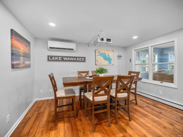 dining space featuring hardwood / wood-style flooring, a baseboard radiator, and a wall mounted AC