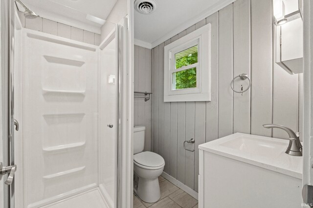 bathroom featuring wooden walls, crown molding, tile patterned floors, toilet, and vanity