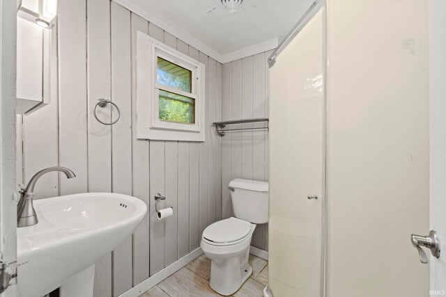 bathroom with sink, wood walls, and toilet