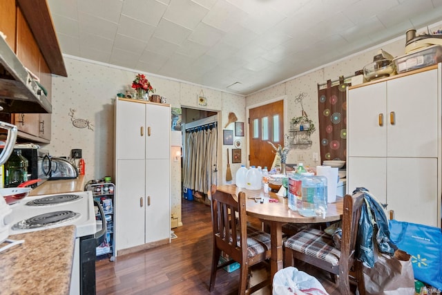 dining area with crown molding, dark wood-type flooring, and wallpapered walls