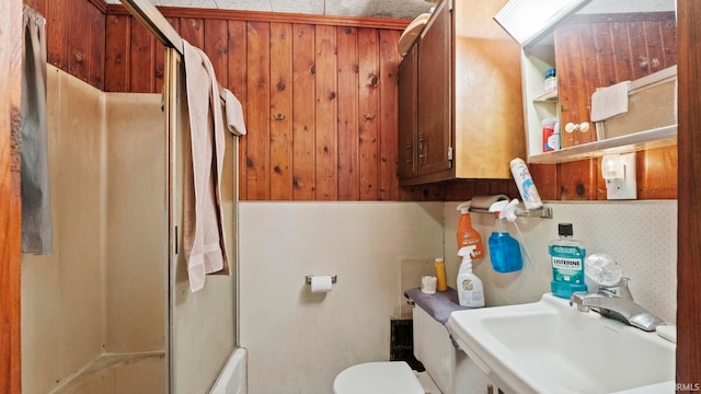 full bath with toilet, wood walls, a shower stall, and a sink