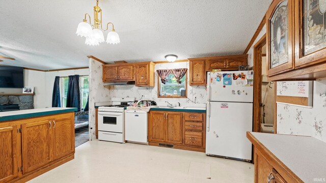 kitchen featuring white appliances, an inviting chandelier, sink, hanging light fixtures, and a textured ceiling