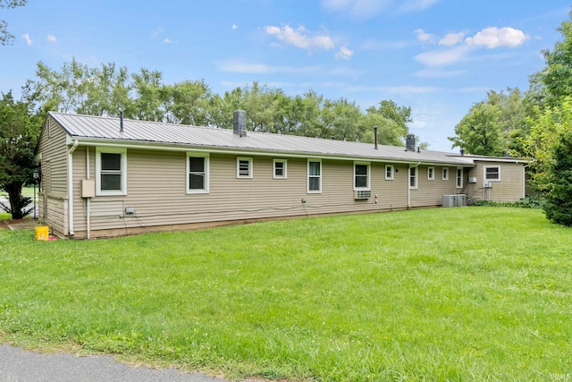 rear view of house featuring metal roof, a yard, and central AC