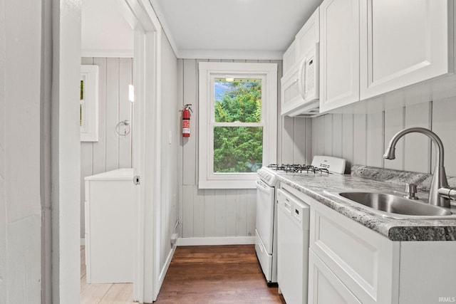 kitchen with white appliances, dark wood-style flooring, a sink, white cabinetry, and baseboards