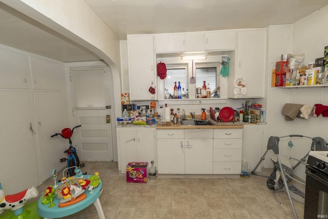 kitchen featuring black gas range oven, sink, and white cabinets