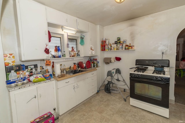 kitchen with sink, gas range oven, and white cabinets