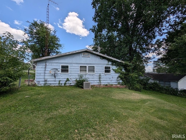 view of side of property featuring central AC and a lawn