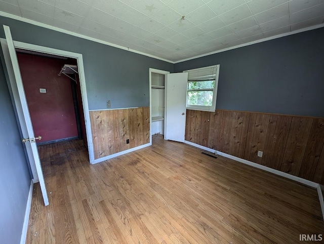 unfurnished bedroom with a closet, hardwood / wood-style flooring, and crown molding