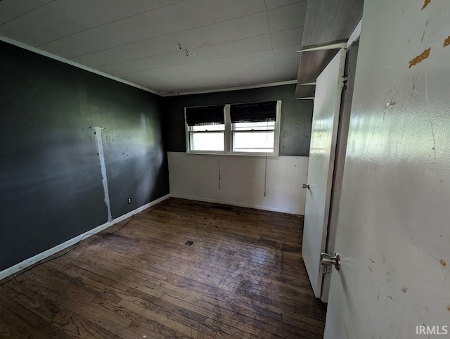 empty room featuring ornamental molding, baseboards, and hardwood / wood-style flooring