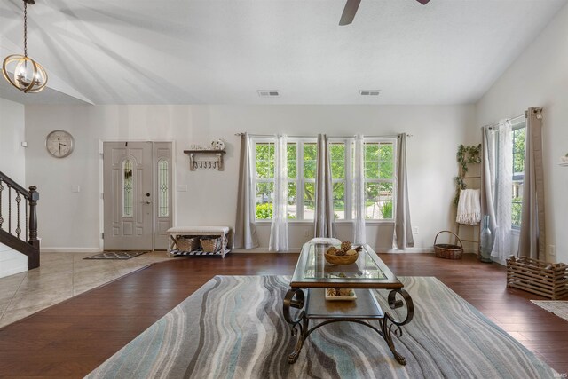 living room featuring ceiling fan with notable chandelier, hardwood / wood-style flooring, and vaulted ceiling