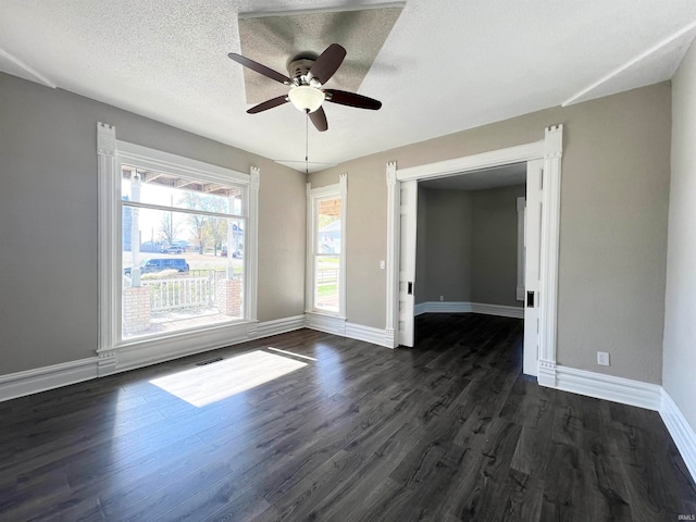 unfurnished bedroom with dark wood-type flooring, a textured ceiling, ceiling fan, and a walk in closet