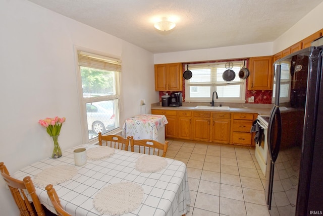 kitchen with tile counters, white electric range, sink, black fridge, and light tile patterned flooring