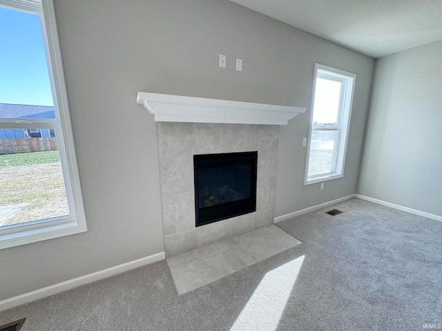 carpeted living room with a tiled fireplace and a wealth of natural light