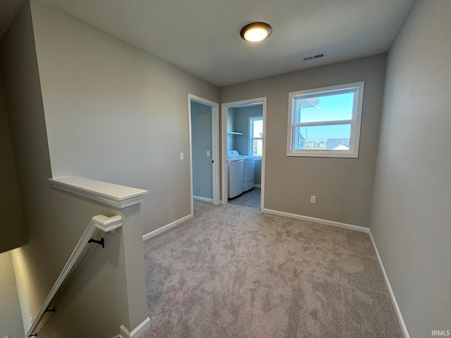 unfurnished room with light colored carpet and washer and clothes dryer