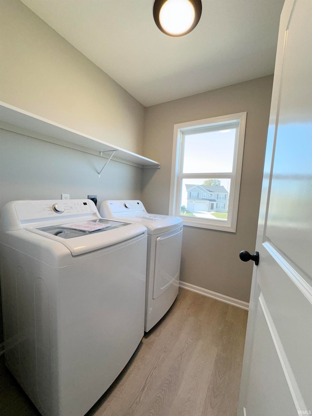 clothes washing area with separate washer and dryer and light hardwood / wood-style floors