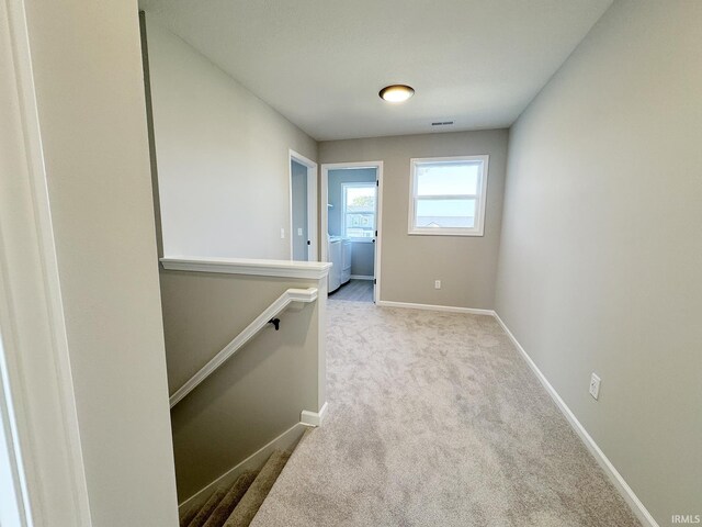 hall with washer / clothes dryer and light colored carpet