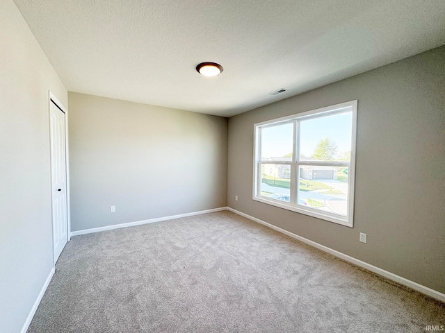 carpeted spare room with a textured ceiling