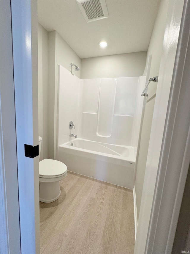 bathroom with wood-type flooring, tub / shower combination, and toilet