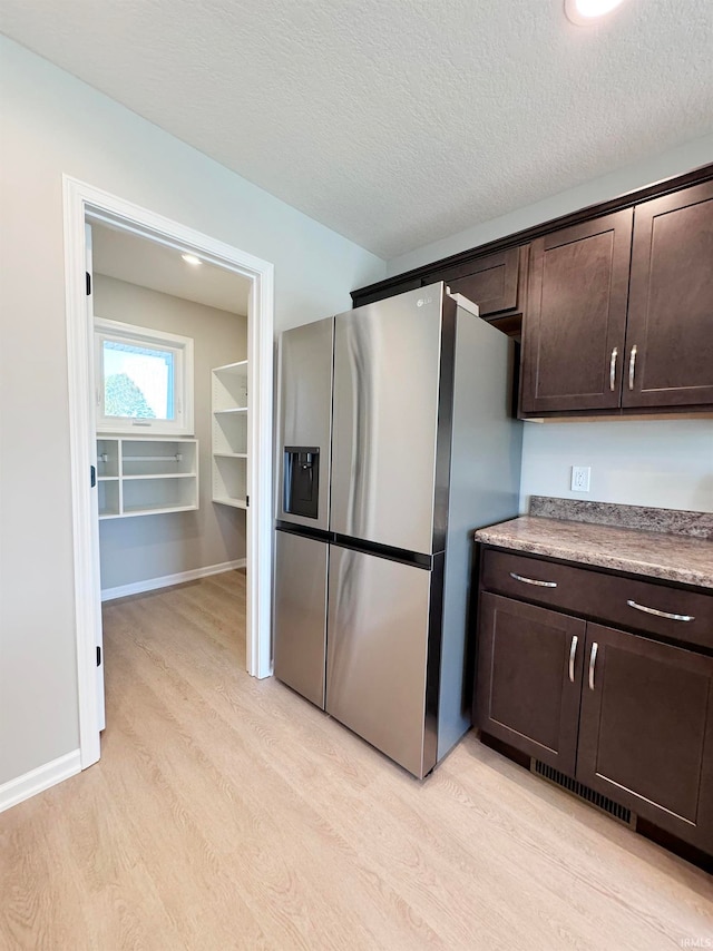 kitchen featuring dark brown cabinetry, stainless steel fridge with ice dispenser, light hardwood / wood-style flooring, and a textured ceiling