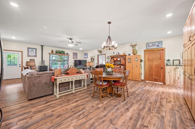 dining area with ceiling fan with notable chandelier and hardwood / wood-style floors