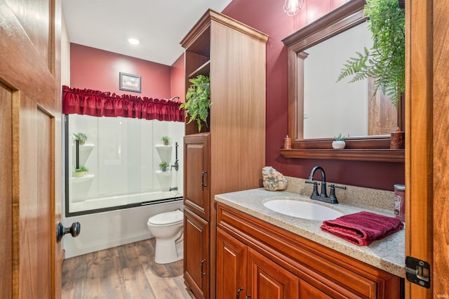 full bathroom featuring combined bath / shower with glass door, wood-type flooring, vanity, and toilet