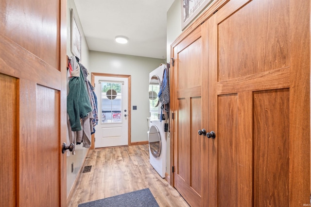 washroom with light hardwood / wood-style flooring and stacked washer and dryer