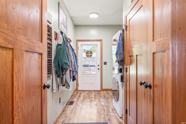 laundry area featuring stacked washer and clothes dryer and light wood-type flooring