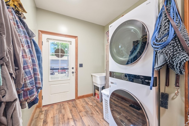 clothes washing area with stacked washer / dryer and light hardwood / wood-style flooring