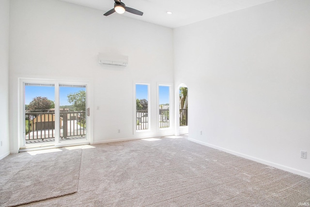 unfurnished living room with carpet floors, a towering ceiling, a wealth of natural light, and ceiling fan