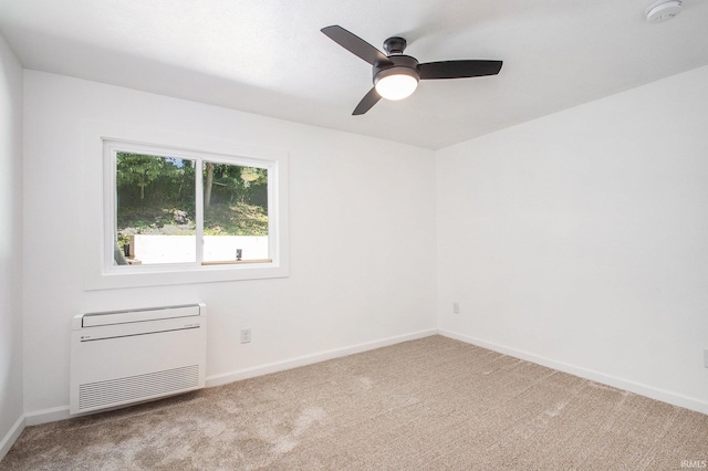 spare room with heating unit, light carpet, and ceiling fan