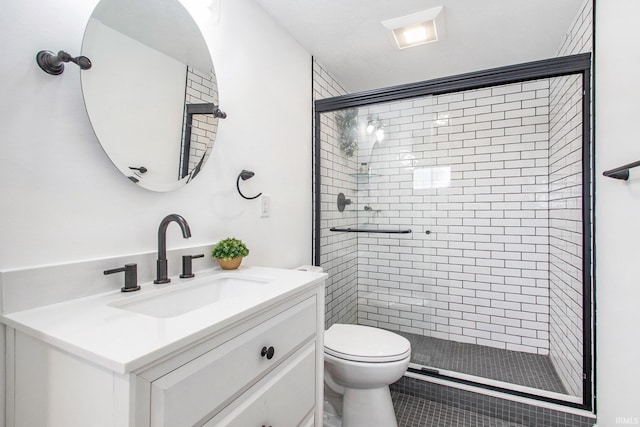 bathroom with a shower with door, vanity, tile patterned flooring, and toilet