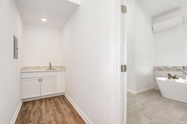 bathroom featuring vanity, hardwood / wood-style flooring, a wall mounted AC, a bathing tub, and electric panel