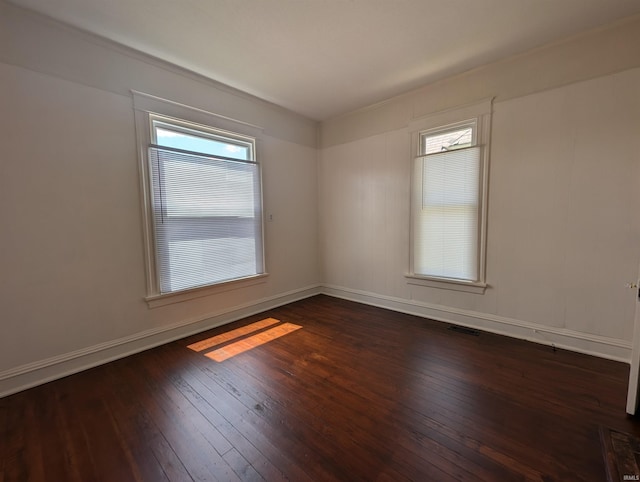 spare room featuring visible vents, wood-type flooring, and baseboards