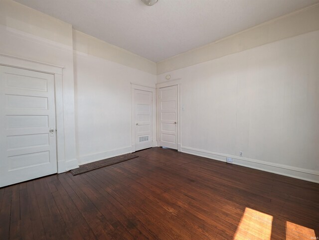 spare room with baseboards and dark wood finished floors