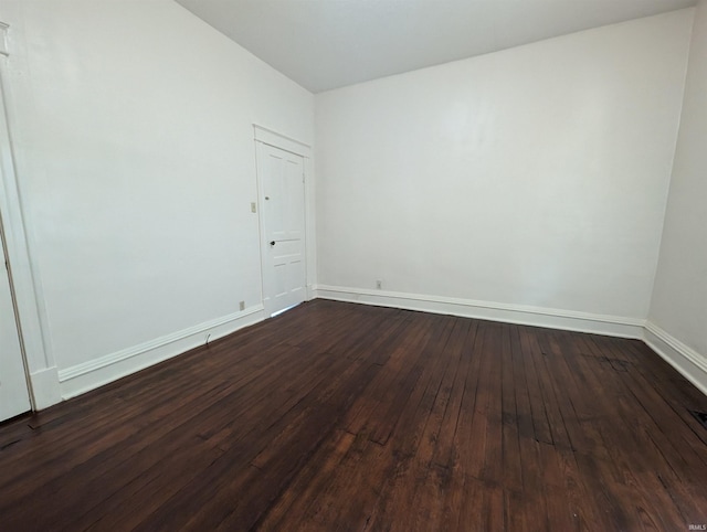 spare room with baseboards and dark wood finished floors