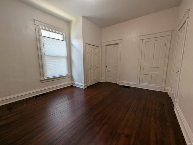 unfurnished bedroom with baseboards, dark wood finished floors, and visible vents