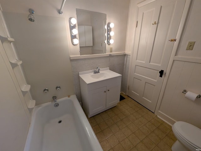 full bath featuring a wainscoted wall, toilet, vanity, and shower / washtub combination