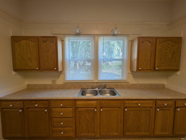 kitchen with brown cabinetry, light countertops, and a sink