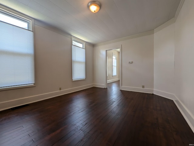 spare room with crown molding, baseboards, and dark wood-style floors