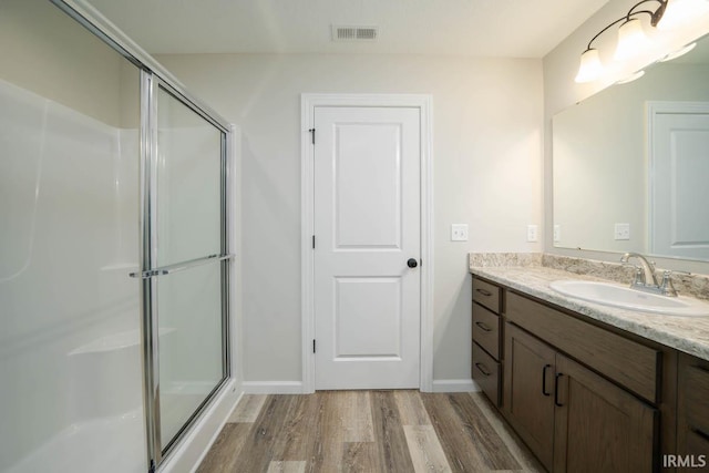 bathroom featuring hardwood / wood-style flooring, vanity, and a shower with shower door