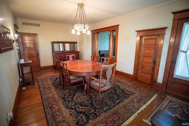 dining room with dark wood-type flooring, ornamental molding, and a notable chandelier