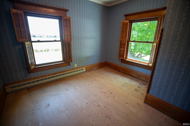 spare room with baseboard heating, hardwood / wood-style floors, and ornamental molding