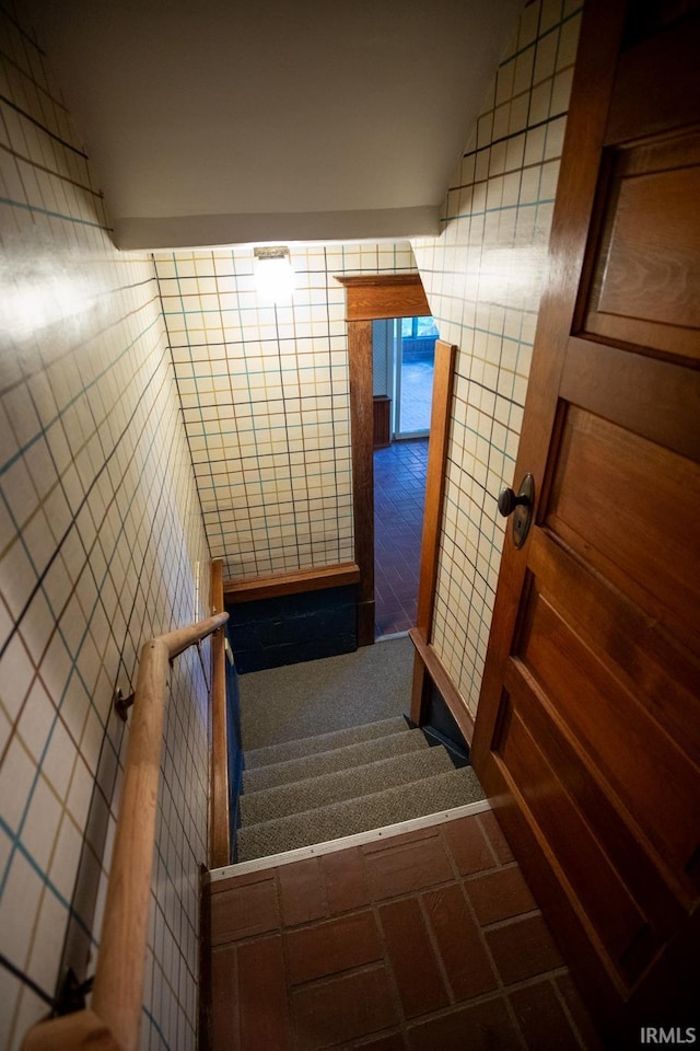 stairway featuring tile walls and tile patterned floors