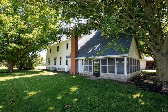 rear view of property featuring a sunroom and a lawn