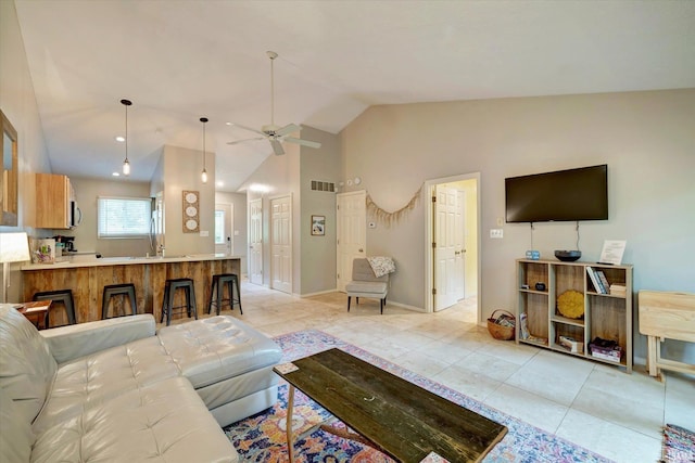 tiled living room with ceiling fan and high vaulted ceiling