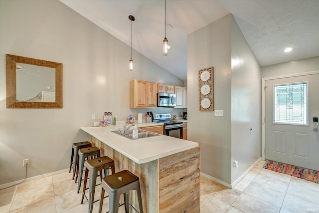 kitchen featuring decorative light fixtures, kitchen peninsula, sink, light brown cabinets, and stainless steel appliances