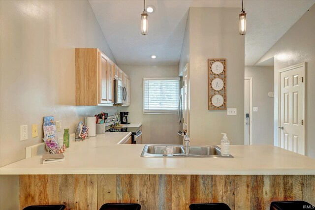 kitchen with decorative light fixtures, stainless steel appliances, sink, kitchen peninsula, and vaulted ceiling